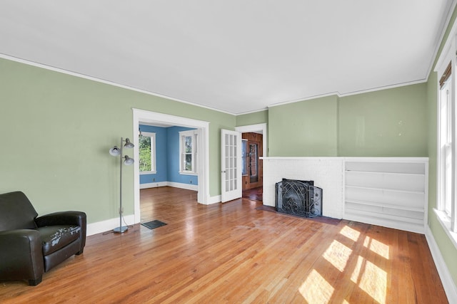 living room featuring visible vents, baseboards, ornamental molding, a fireplace, and wood finished floors