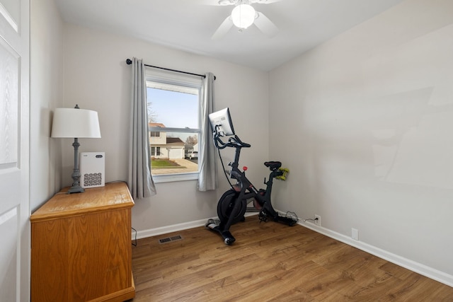 exercise room featuring light wood-type flooring, visible vents, a ceiling fan, and baseboards