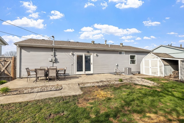 back of house featuring fence, a patio area, a storage unit, and an outbuilding