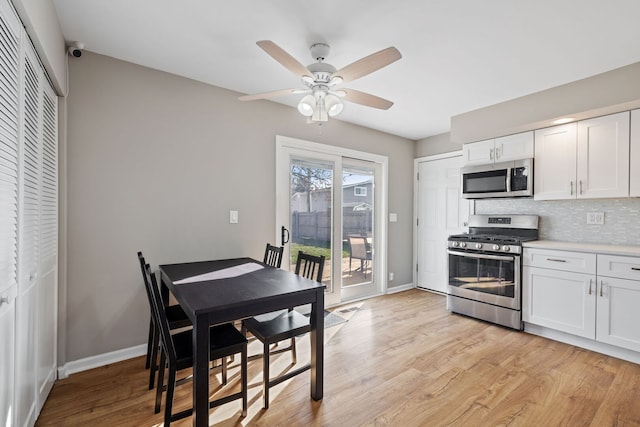 kitchen featuring stainless steel appliances, light wood-type flooring, white cabinetry, decorative backsplash, and a ceiling fan