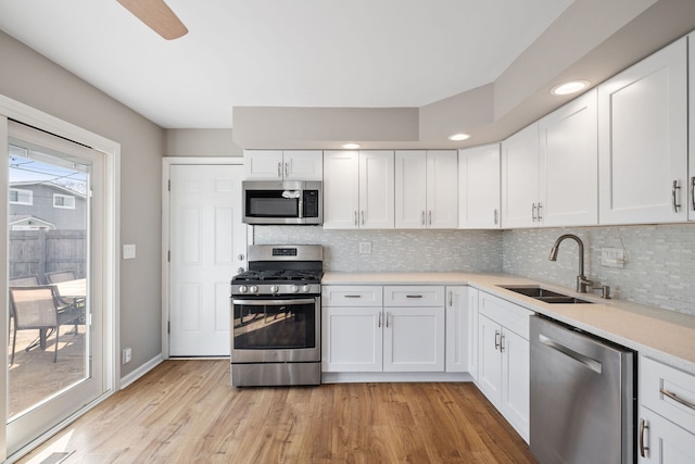 kitchen with a sink, white cabinetry, decorative backsplash, light countertops, and appliances with stainless steel finishes