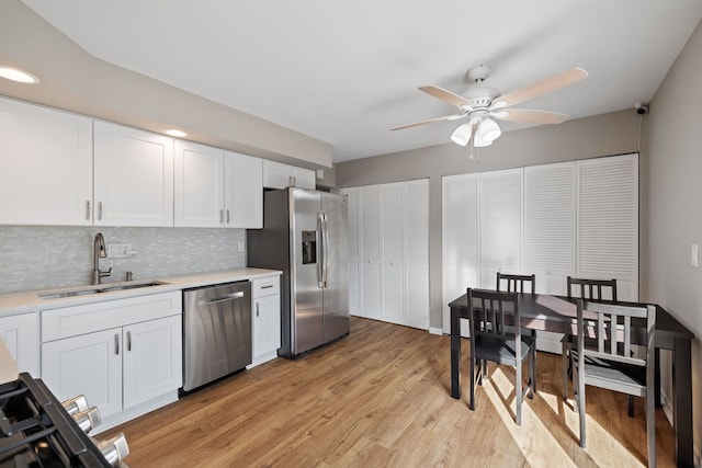 kitchen featuring stainless steel appliances, light countertops, white cabinetry, a sink, and ceiling fan