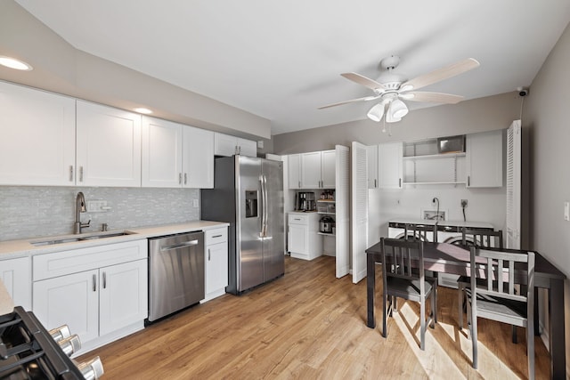 kitchen with a sink, ceiling fan, stainless steel appliances, light countertops, and white cabinetry