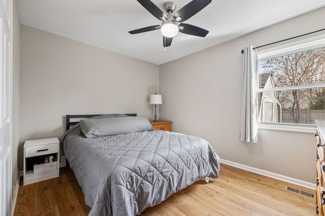 bedroom featuring wood finished floors, visible vents, a ceiling fan, and baseboards