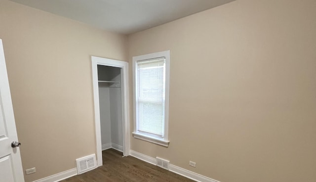 325 W 107th St, Chicago, IL 60628 - unfurnished bedroom featuring multiple windows, baseboards, dark wood-type flooring, and a closet