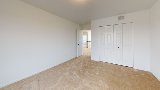 unfurnished bedroom featuring a closet, carpet flooring, baseboards, and visible vents