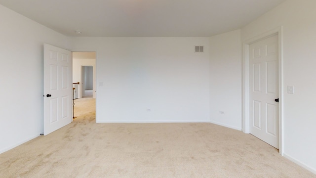 spare room with light colored carpet, baseboards, and visible vents