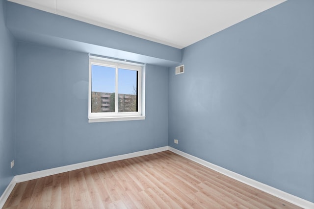 spare room featuring baseboards, visible vents, and light wood-style floors