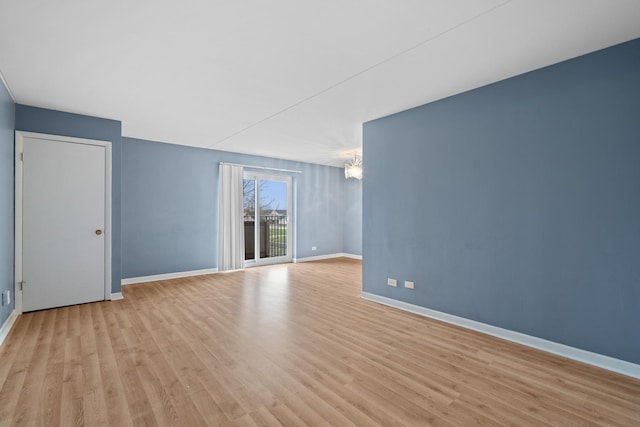 unfurnished room with baseboards, light wood-style flooring, and a chandelier