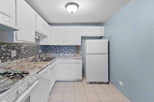 kitchen with tasteful backsplash, white appliances, light tile patterned floors, a sink, and white cabinets