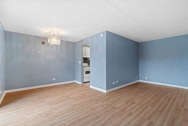 interior space with baseboards, a notable chandelier, and light wood finished floors