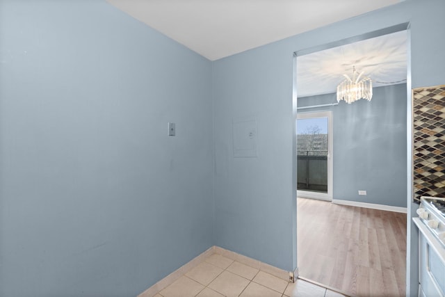 unfurnished room with baseboards, a chandelier, and light tile patterned floors