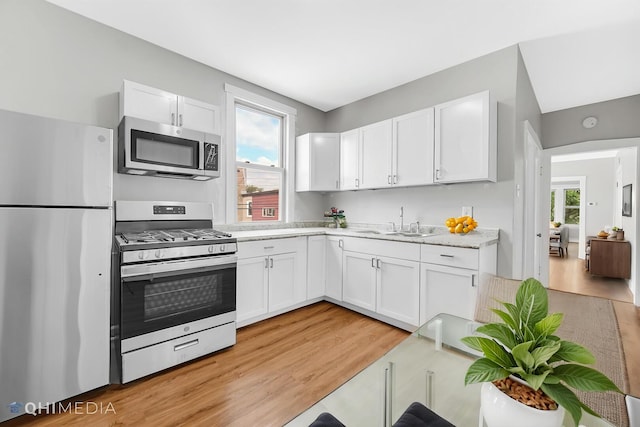 kitchen with light countertops, stainless steel appliances, white cabinetry, and a sink