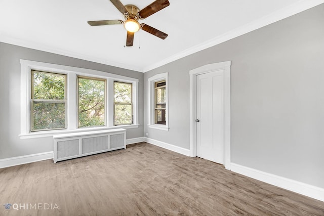 unfurnished room with ceiling fan, wood finished floors, baseboards, radiator heating unit, and ornamental molding