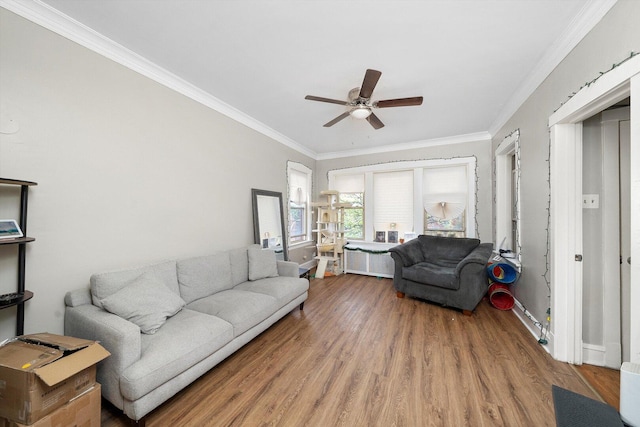 living area featuring crown molding, baseboards, a ceiling fan, and wood finished floors