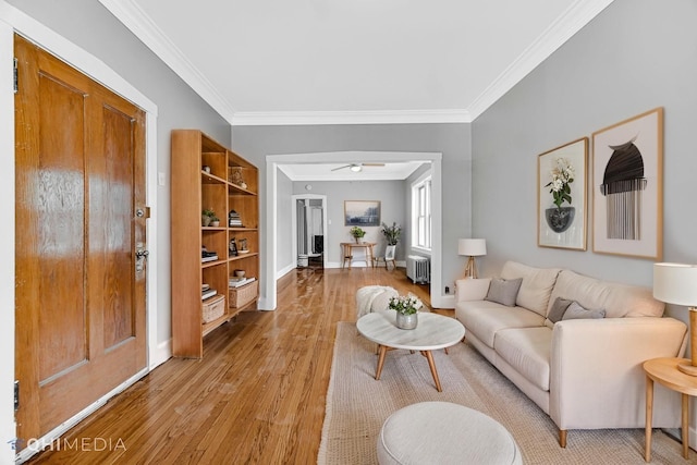 living room with crown molding, ceiling fan, light wood-style flooring, radiator, and baseboards
