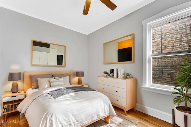 bedroom with light wood-style floors, a ceiling fan, and baseboards