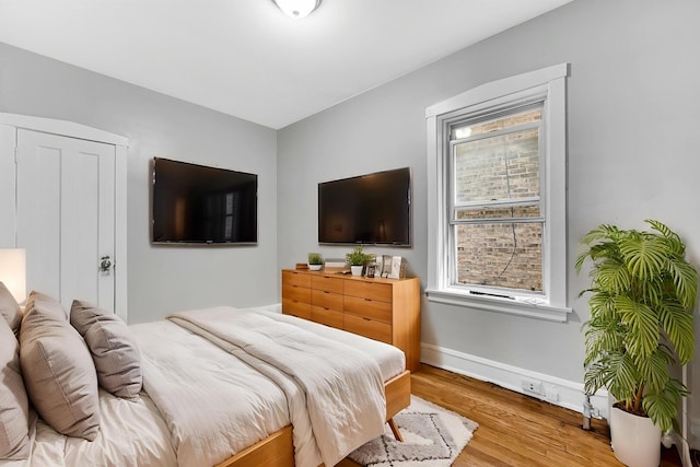 bedroom with baseboards, multiple windows, and wood finished floors