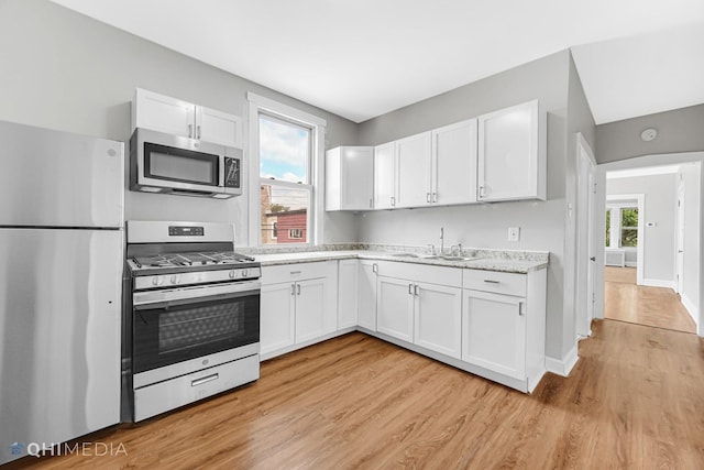 kitchen with a sink, light countertops, light wood-style floors, and stainless steel appliances
