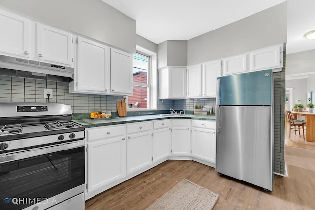 kitchen with tasteful backsplash, white cabinets, under cabinet range hood, stainless steel appliances, and light wood-style flooring