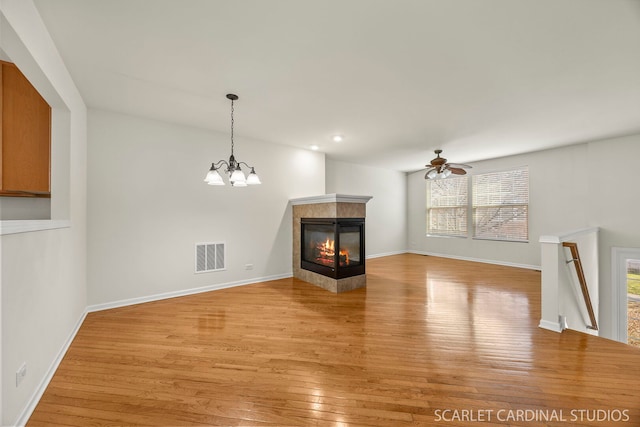 1045 Crane Pt, Elgin, IL 60124 - unfurnished dining area featuring light wood-type flooring, baseboards, a fireplace, visible vents, and ceiling fan with notable chandelier