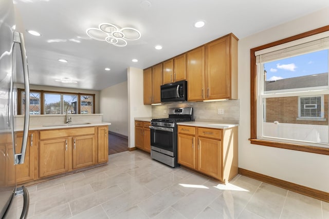 kitchen with plenty of natural light, light countertops, a sink, and appliances with stainless steel finishes