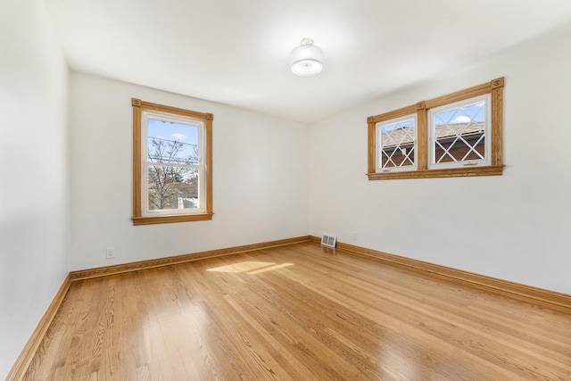 empty room featuring visible vents, baseboards, and wood finished floors