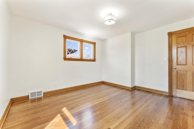 unfurnished room featuring visible vents, baseboards, and wood finished floors