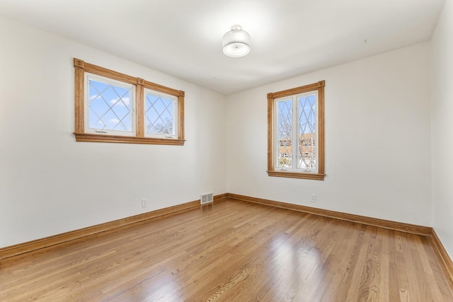 unfurnished room featuring light wood-type flooring, baseboards, and visible vents