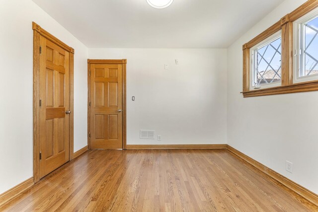 unfurnished room featuring light wood finished floors, baseboards, and visible vents