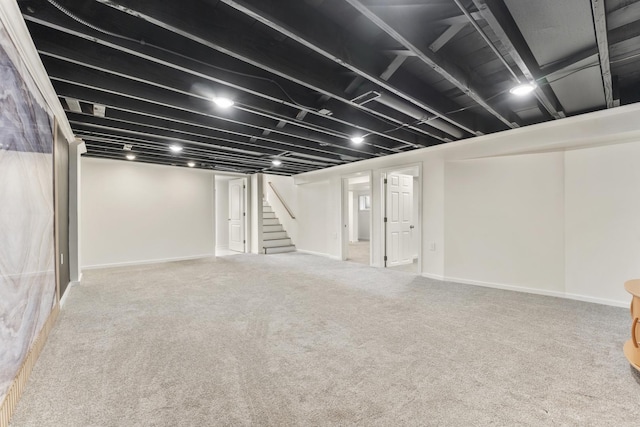 finished below grade area featuring baseboards, carpet flooring, and stairs