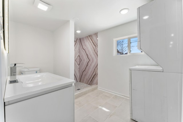 full bathroom featuring vanity, recessed lighting, a stall shower, baseboards, and stacked washer / drying machine