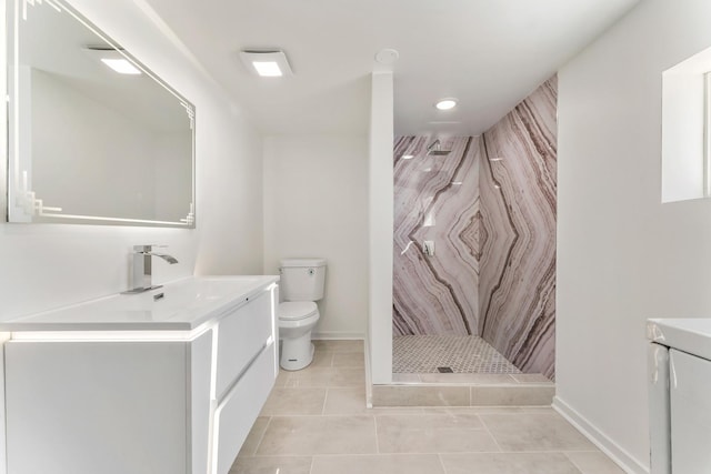 bathroom with baseboards, toilet, vanity, a marble finish shower, and tile patterned flooring