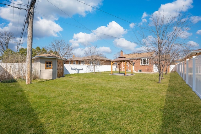 view of yard featuring a gazebo, a storage unit, a fenced backyard, and an outbuilding