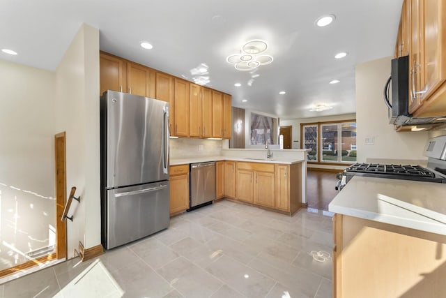 kitchen with tasteful backsplash, a sink, light countertops, appliances with stainless steel finishes, and a peninsula