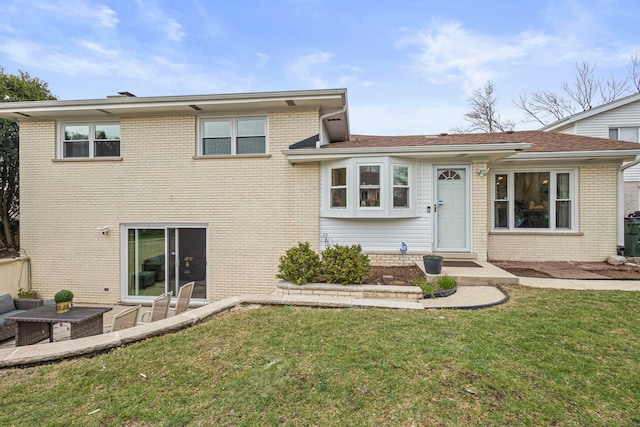 back of house featuring brick siding and a yard