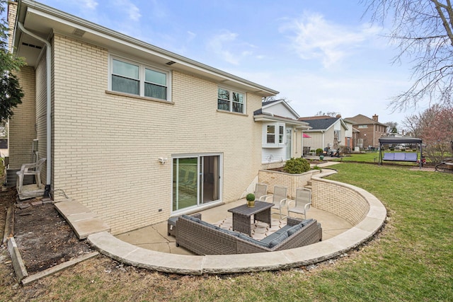 back of house featuring brick siding, a yard, and a patio