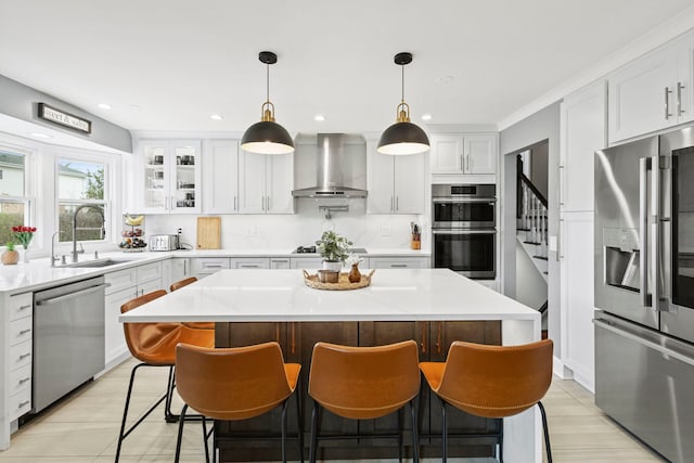 kitchen with wall chimney exhaust hood, white cabinets, a sink, and appliances with stainless steel finishes