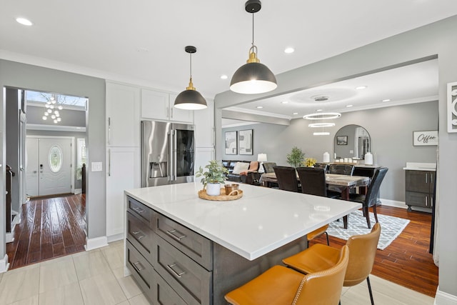 kitchen featuring white cabinets, light countertops, pendant lighting, and stainless steel fridge with ice dispenser