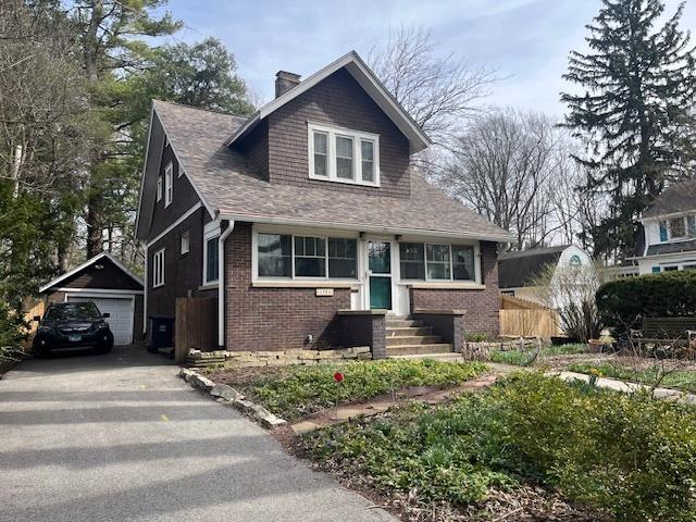 1204 S Carle Ave, Urbana, IL 61801 - bungalow-style home with roof with shingles, brick siding, a chimney, an outdoor structure, and driveway