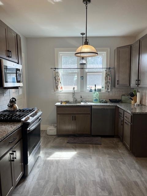 1204 S Carle Ave, Urbana, IL 61801 - kitchen featuring decorative backsplash, pendant lighting, light stone counters, a sink, and appliances with stainless steel finishes