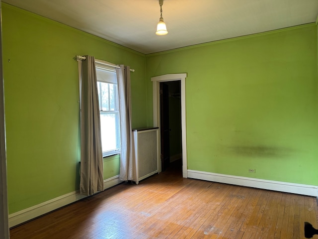spare room featuring baseboards, radiator, and hardwood / wood-style floors