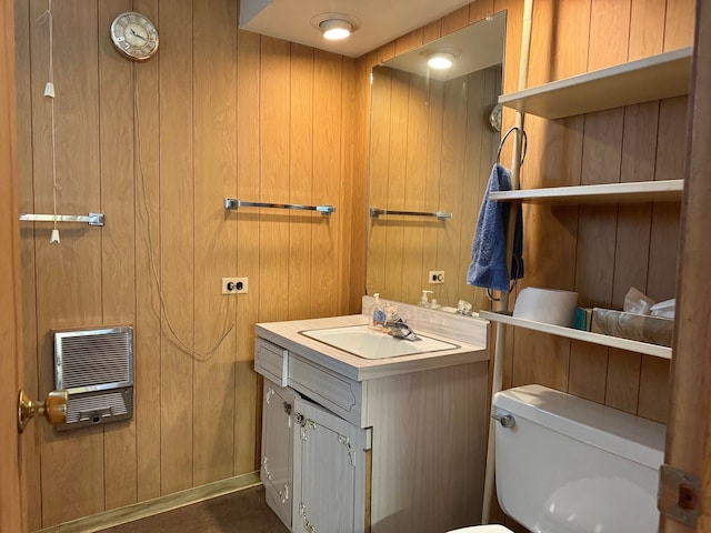 bathroom with heating unit, wooden walls, toilet, and vanity