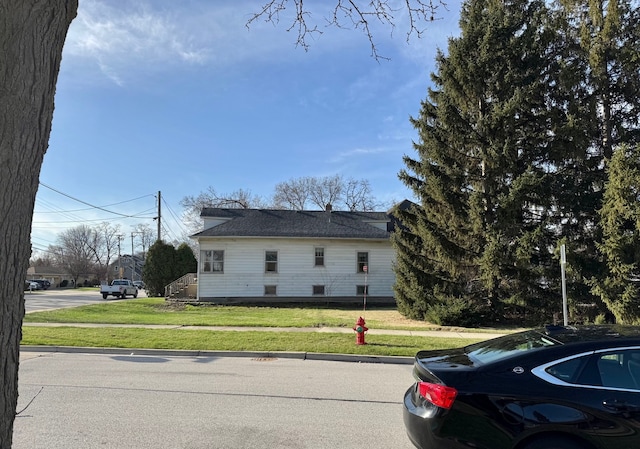view of front of property featuring a front lawn and roof with shingles