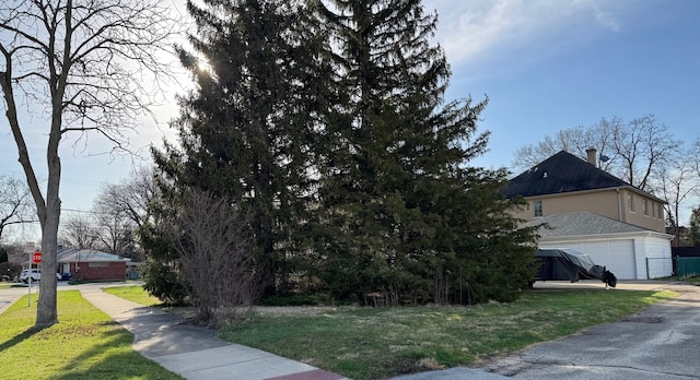 view of home's exterior featuring a shingled roof, concrete driveway, a garage, and a lawn