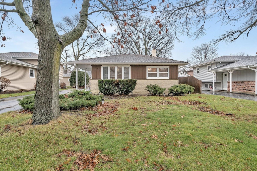 view of front of property with a chimney, brick siding, and a front lawn