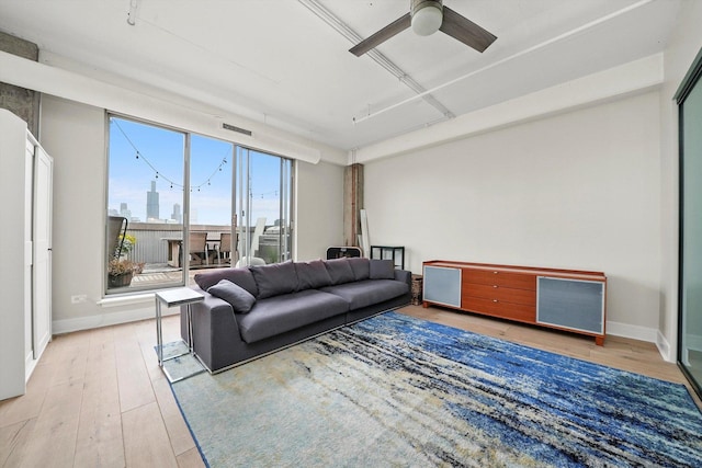 living room with baseboards, hardwood / wood-style flooring, ceiling fan, visible vents, and a view of city