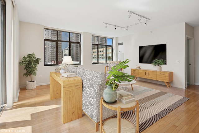 living area featuring light wood-type flooring, track lighting, and baseboards