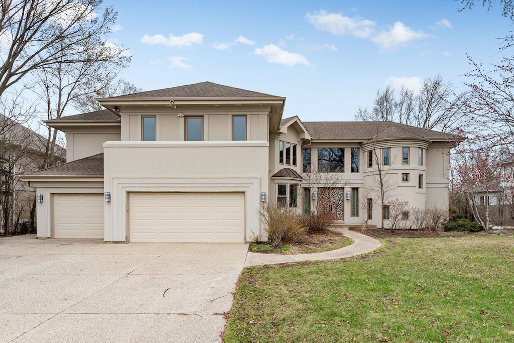 view of front of property featuring a shingled roof, a garage, stucco siding, a front lawn, and driveway