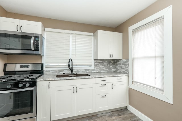 kitchen featuring white cabinets, a sink, stainless steel appliances, and backsplash